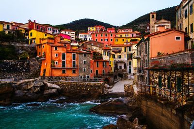 Houses by river in city against clear sky