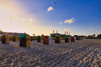 Hooded beach chairs on sand against sky