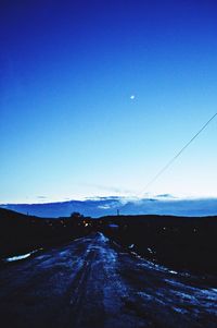 Road leading towards mountains against blue sky