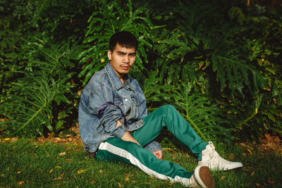 Portrait of young man sitting on field at park