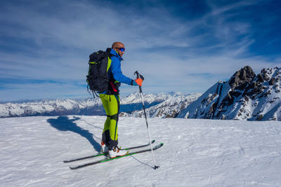 Man skiing on snowcapped mountain against sky