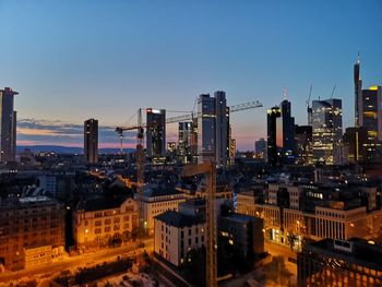 Illuminated buildings in city against clear sky