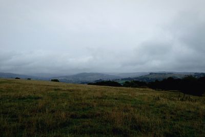 Scenic view of grassy field against cloudy sky