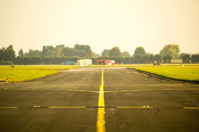 Road amidst field against clear sky