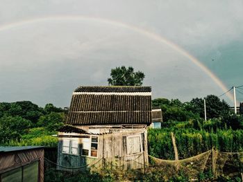 Scenic view of rainbow over building and trees against sky