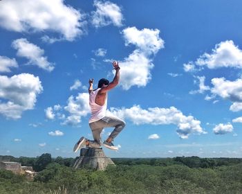 Man with arms raised against sky