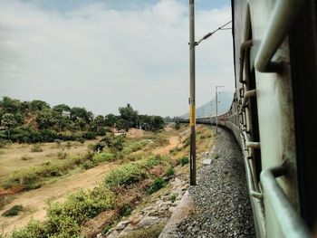 Railroad tracks by trees against sky