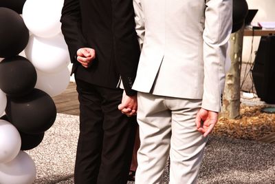 Midsection of couple holding hands while standing on field