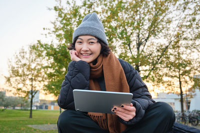 Young woman using laptop while sitting on field