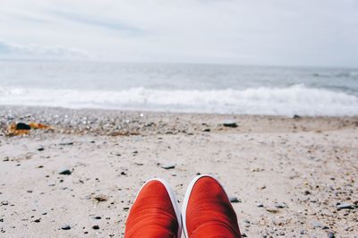 Close-up of shoes on beach against sea