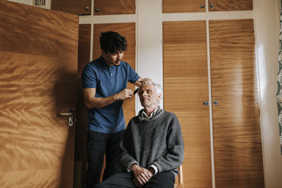 Male healthcare worker taking care of senior man sitting at home