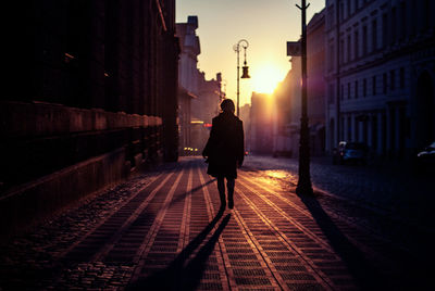 Rear view of silhouette man walking on street in city