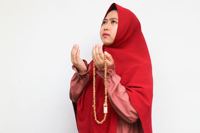 Portrait of young woman standing against white background