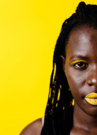 Close-up portrait of woman against yellow background