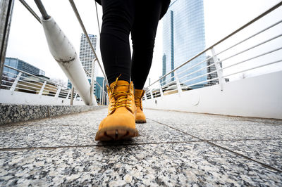 Low section of person on bridge against buildings in city