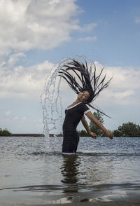 Full length of young woman in water against sky