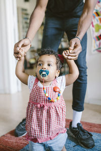 Low section of father assisting daughter in walking at home