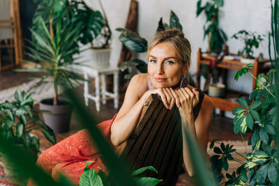 Portrait of a beautiful happy woman sitting on a wooden chair among plants.