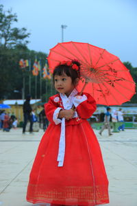 Cute girl standing with red umbrella