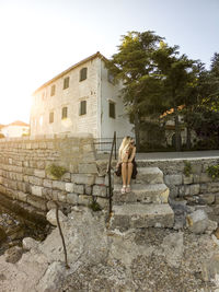 Side view of woman against the wall of building