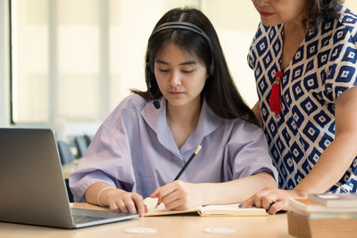 Young woman using phone while sitting on table