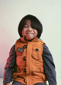 Portrait of boy wearing warm clothing sitting against white background