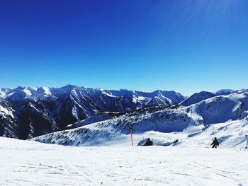 Scenic view of snowcapped mountains against blue sky