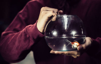 Midsection of woman holding fishbowl