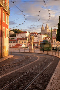 Railroad tracks by buildings in city against sky