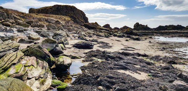 Rock formation on beach against sky