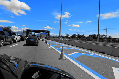 Cars on road in city against blue sky