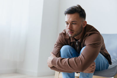 Young man sitting on bed at home