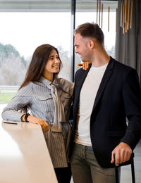 Young couple standing against window