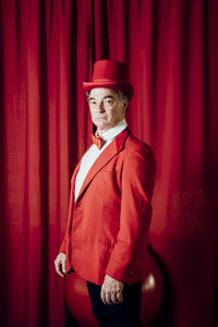 Male artist wearing hat standing by stage curtain