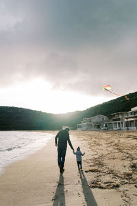 Rear view of man standing on beach against sky