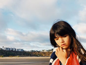 Close-up of thoughtful girl with wrapped in towel against cloudy sky