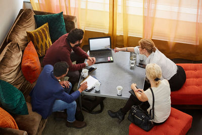 High angle view of female entrepreneur discussing with colleagues while sitting by table in office seminar