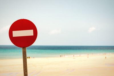 Close-up of do not enter sign at beach against sky