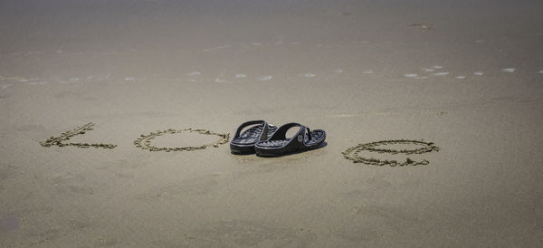 Close-up of text on heart shape on sand