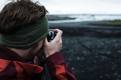 Rear view of man photographing at beach