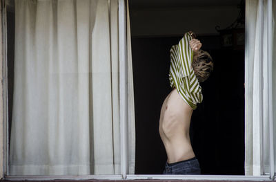 Rear view of woman standing by window