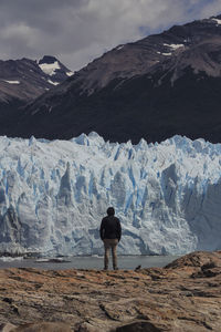 Rear view of man on snowcapped mountain against sky