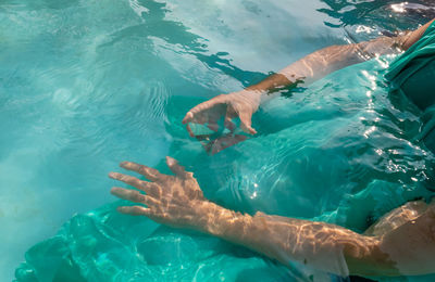 Cropped hand of woman holding pyramid crystal in swimming pool