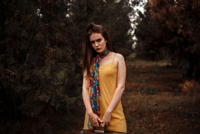 Young woman standing by tree in forest