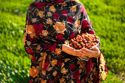 Midsection of man holding fruit on field