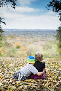 Rear view of friends sitting on land