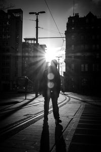 Man walking on street in city against sky