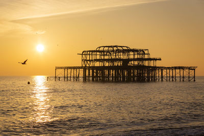 Silhouette pier over sea against sky during sunset