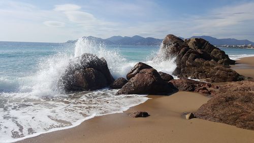 Waves splashing on shore against sky