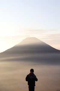 Rear view of man standing on mountain against sky